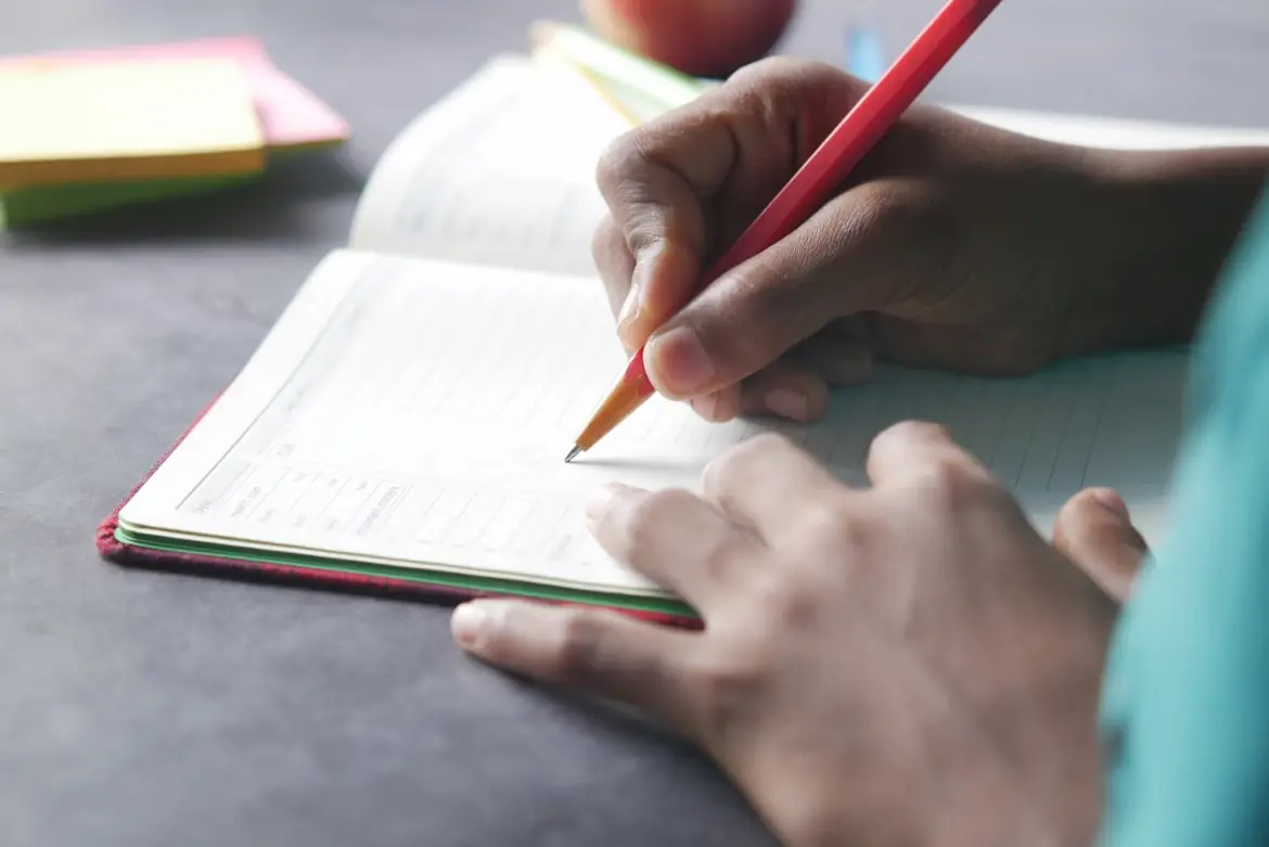 image of a hand writing something on a notebook